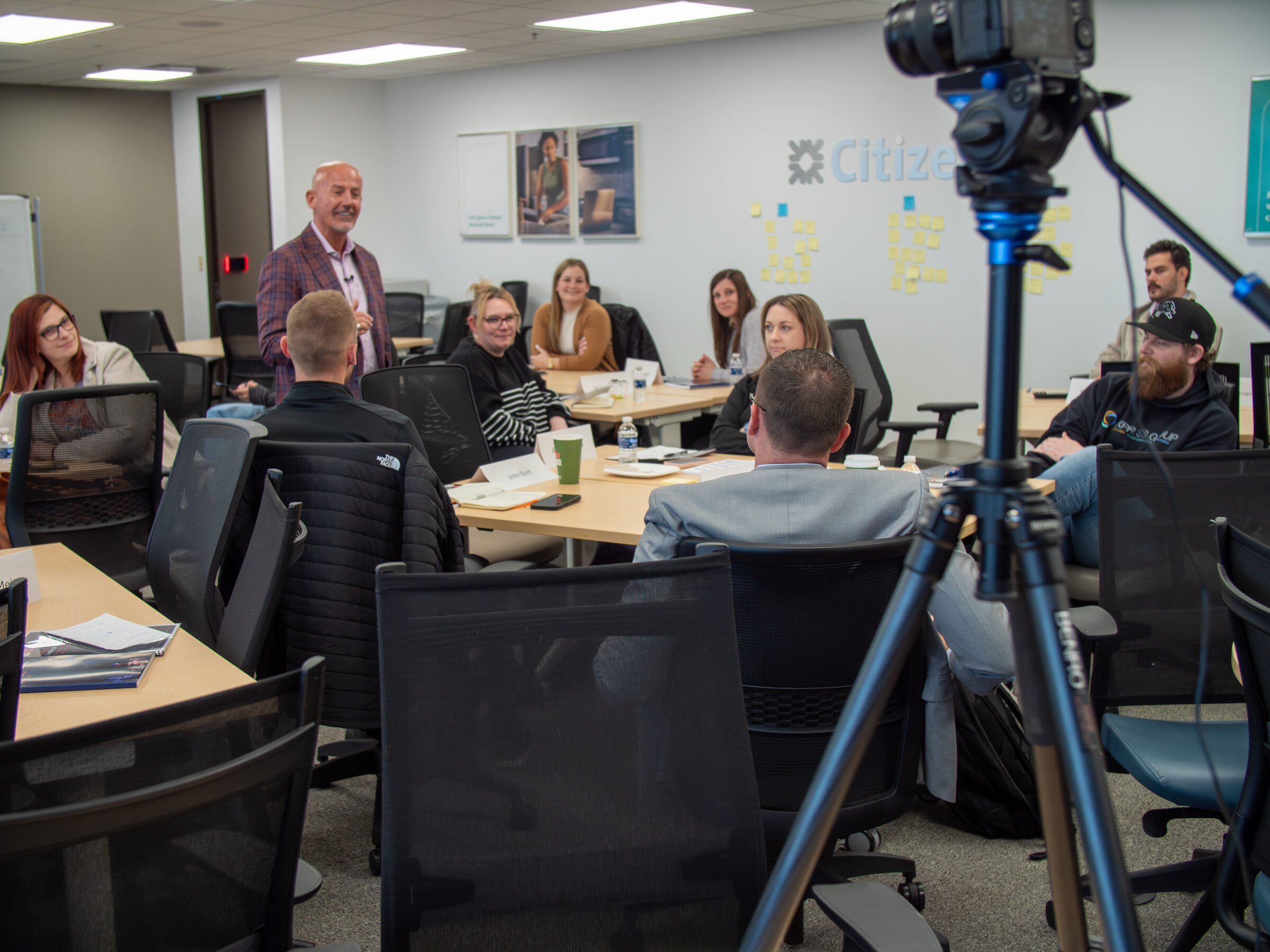 Steve Lowisz working with a client team in the room, holding the 6-Step Performance Engine standard